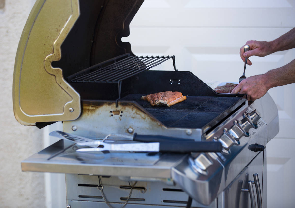 Kenny Atcheson grills outside of his home while participating in a neighborhood front yard part ...