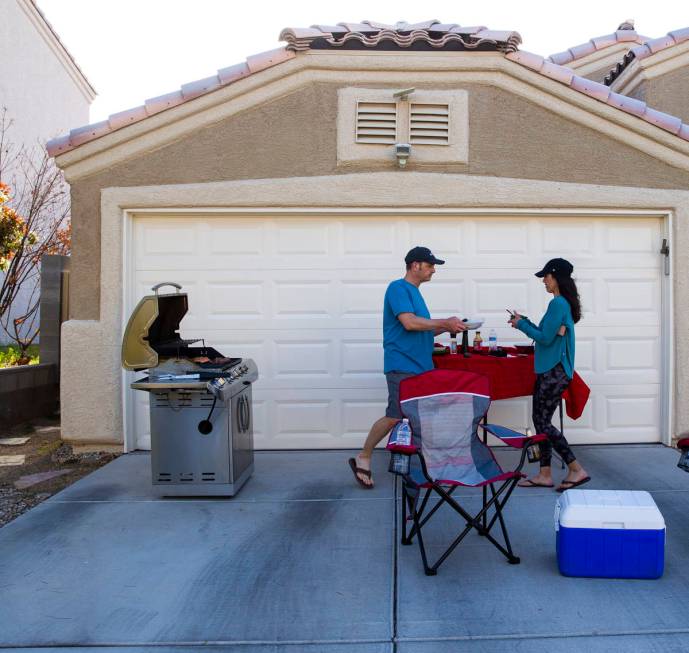 Kenny Atcheson and Jean Atcheson grill outside of their home while participating in a neighborh ...