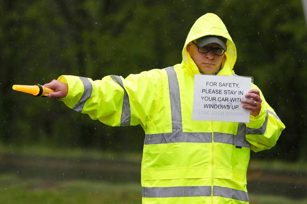 Lou Mills directs traffic as worshipers arrive for a drive-in Easter service at Jenkins Cumberl ...