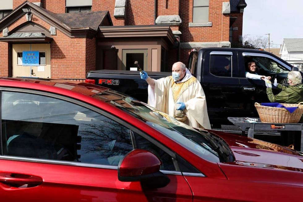 Rev. William Schipper, pastor of Mary, Queen of the Rosary Parish, center, wears a mask and glo ...