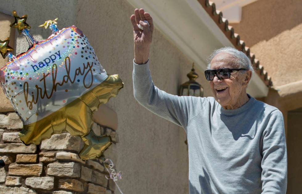 Henry Kronberg waves to friends stopping by his home to help him celebrate his 100th birthday d ...