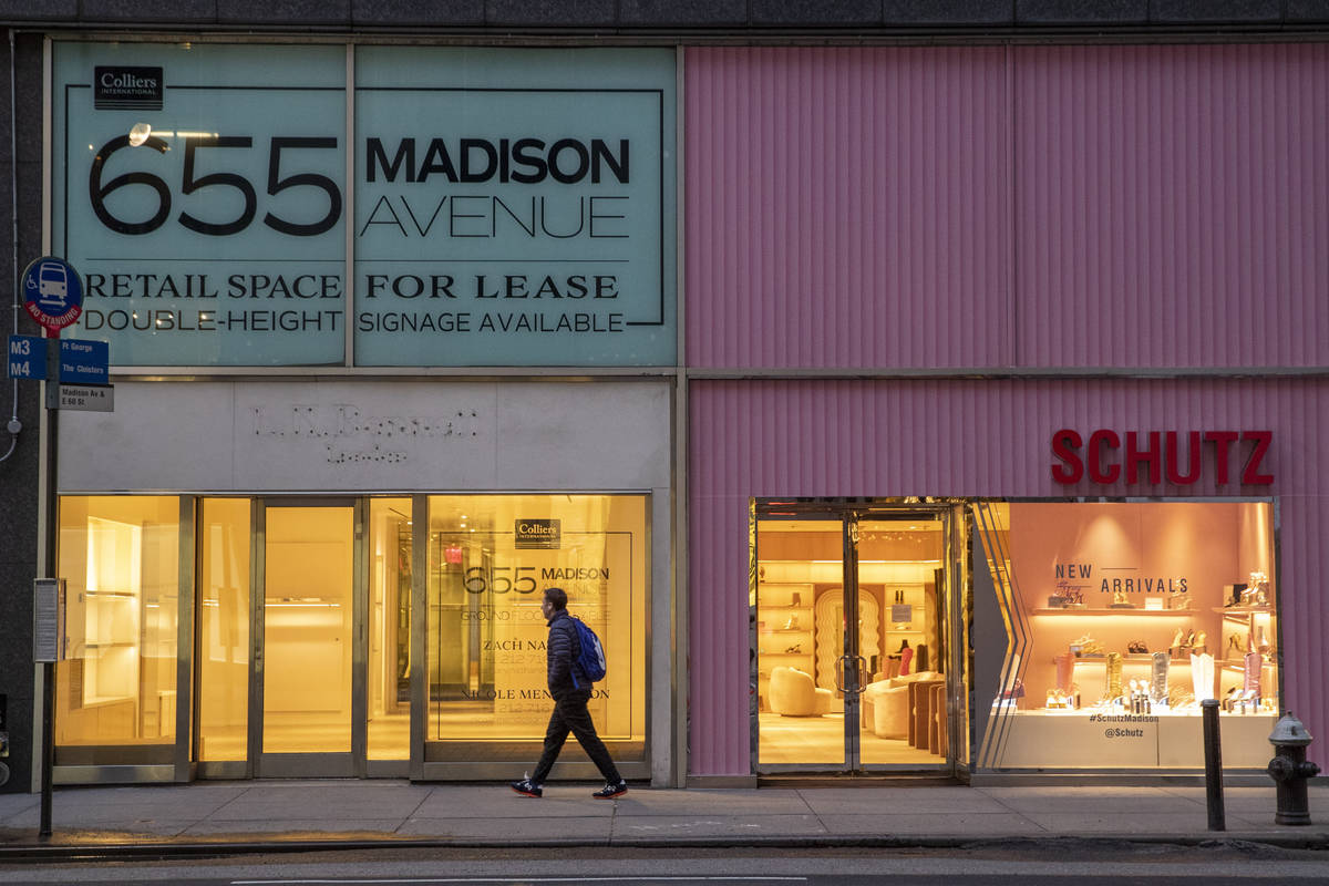 In a Thursday, March 19, 2020, photo, a pedestrian walks past a storefront for rent on Madison ...