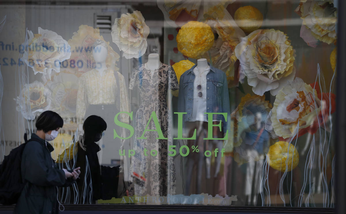 A woman wearing a face mask walks past a closed shop on Oxford Street in London, as the country ...