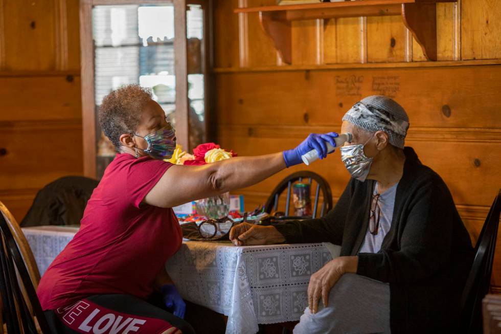 Kismet Evans takes the temperature of her mother, Pauline Evans, at their kitchen table on Thur ...