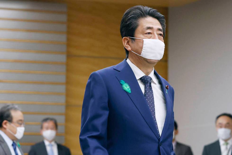 Japanese Prime Minister Shinzo Abe wearing a face mask walks to attend a video conference with ...