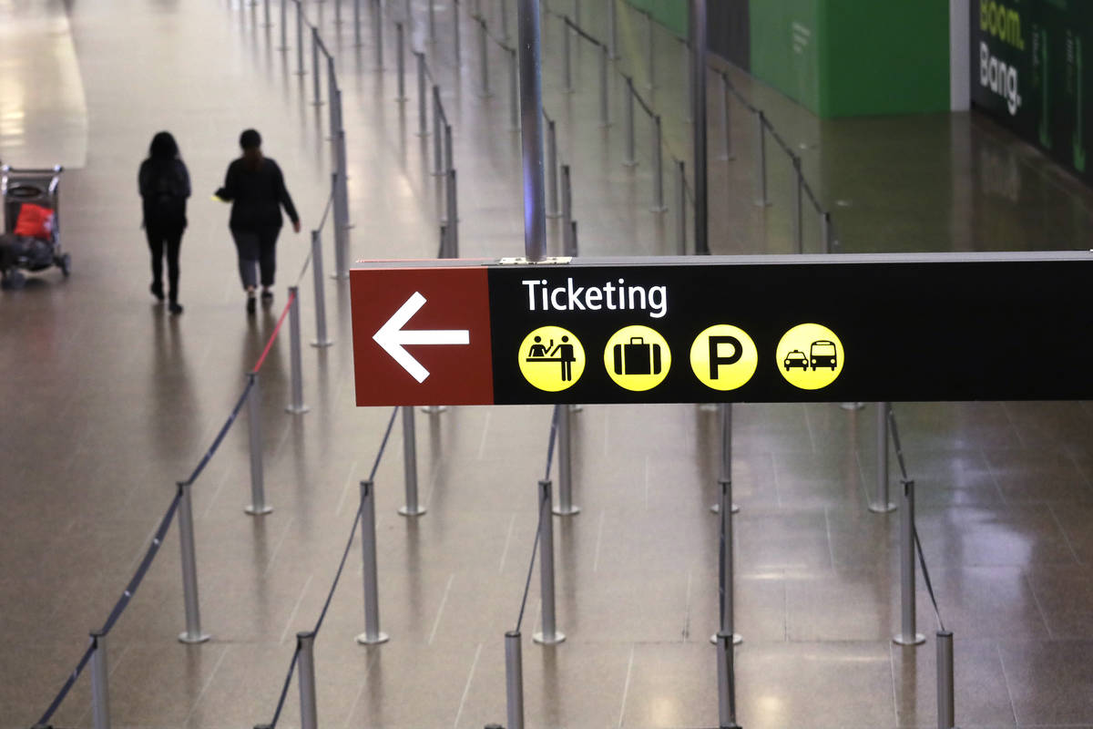 Two people walk past an area meant for hundreds to wait for screening at Seattle-Tacoma Interna ...