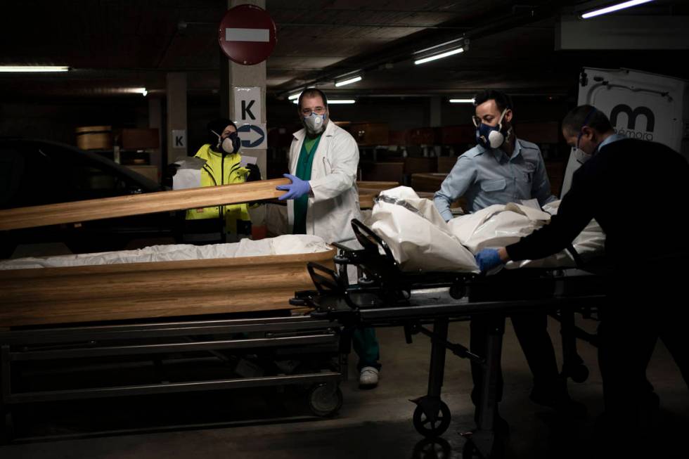 In this April 14, 2020, photo, head mortician Jordi Fernandez, center, closes the coffin of a C ...