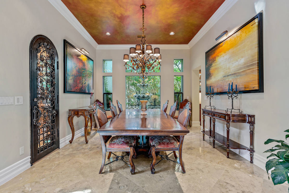 The formal dining room features a handpainted ceiling, custom chandelier, temperature-controlle ...