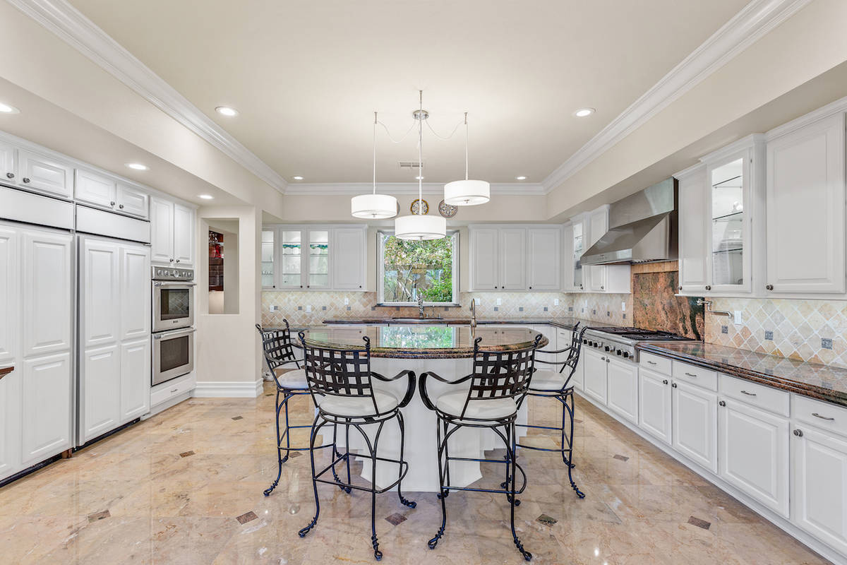 The kitchen has an oversized tiered island, Verde Fire marble countertops, new professional-gra ...