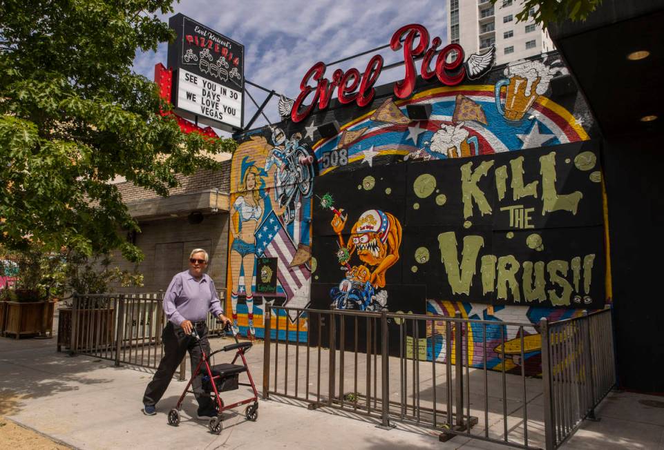 A pedestrian walks past a closed Evel Pie on an empty Fremont Street in Downtown Las Vegas duri ...