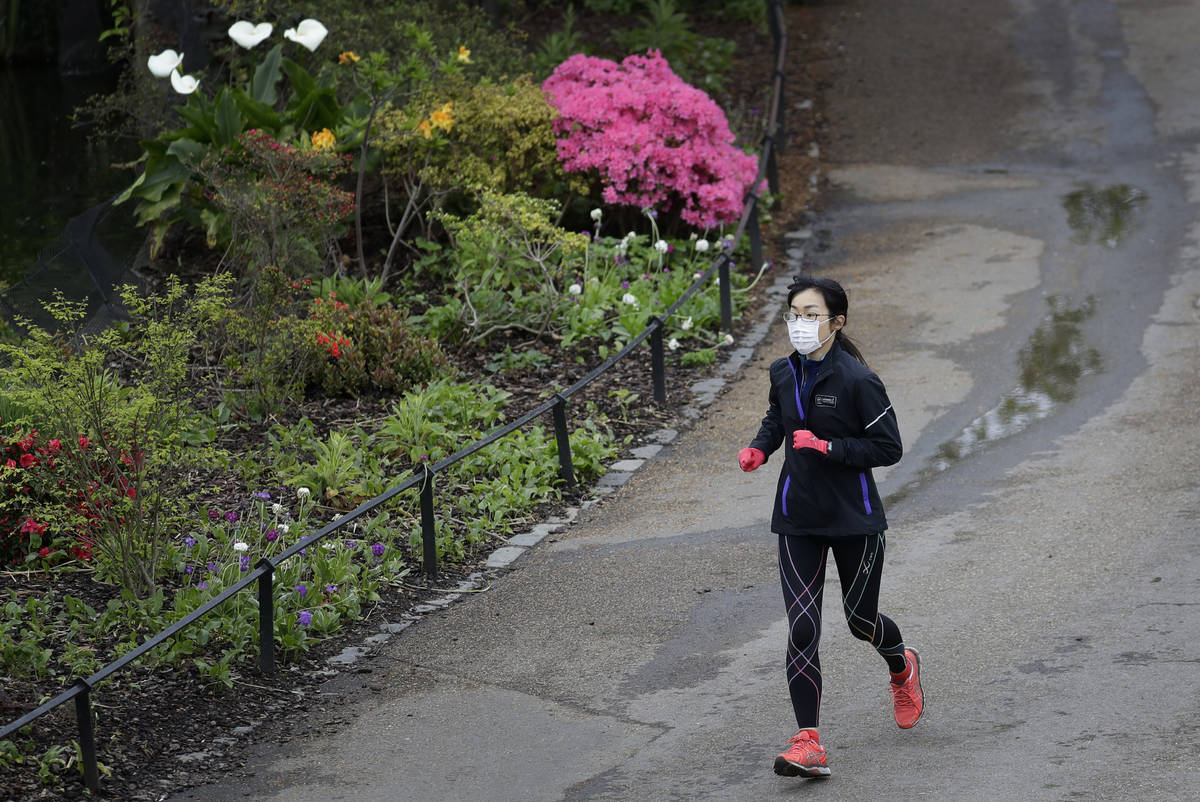 A jogger wears a protective face mask to protect against coronavirus, runs through St James's P ...