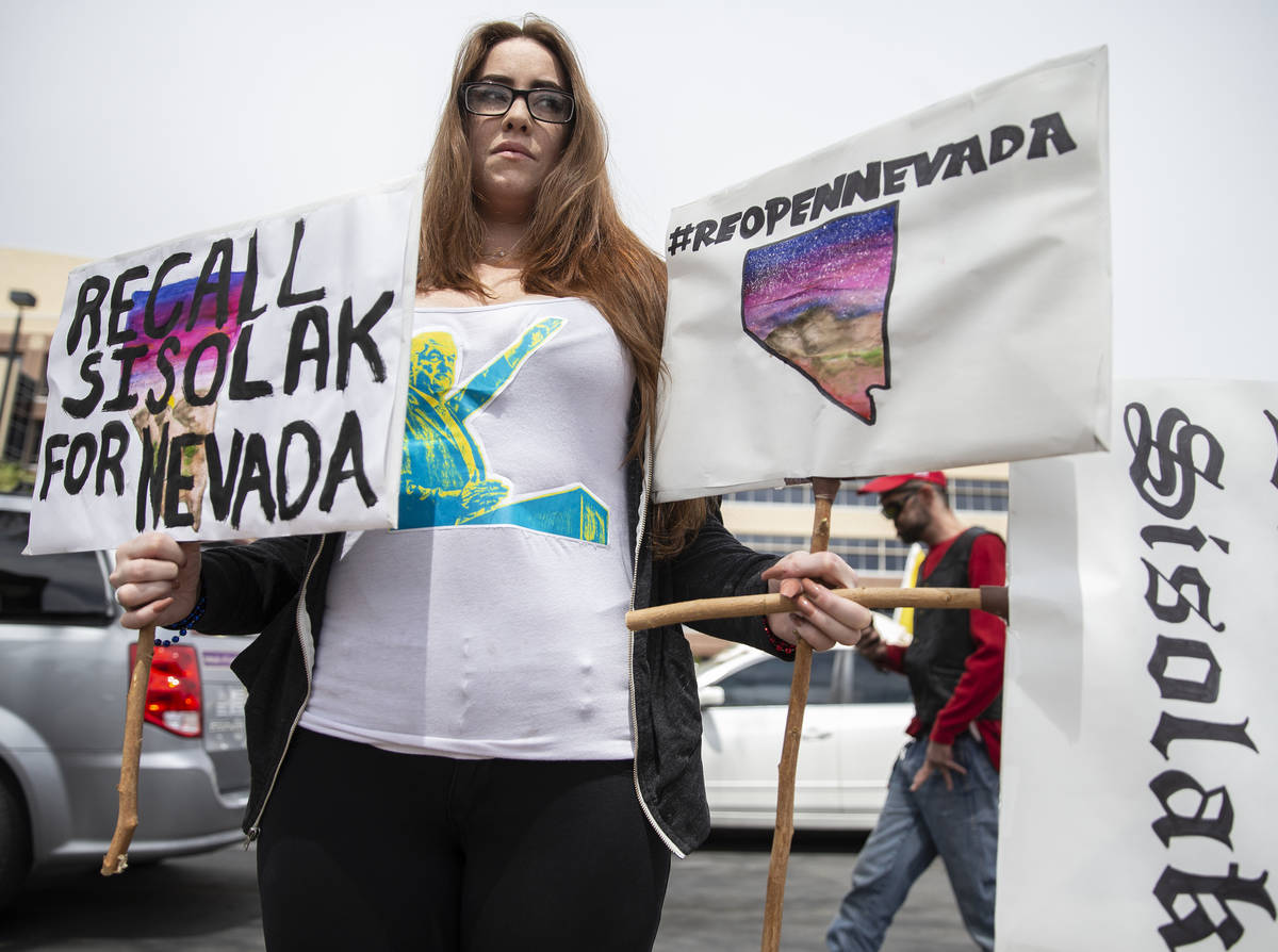 Natalie Thomas, the Facebook organizer of the Reopen Nevada event, holds signs opposing Gov. St ...