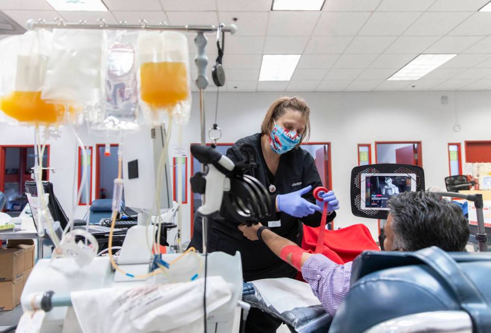 Phlebotomist Courtney Gaudette, left, wraps the arm of a man that donated plasma at Vitalant on ...