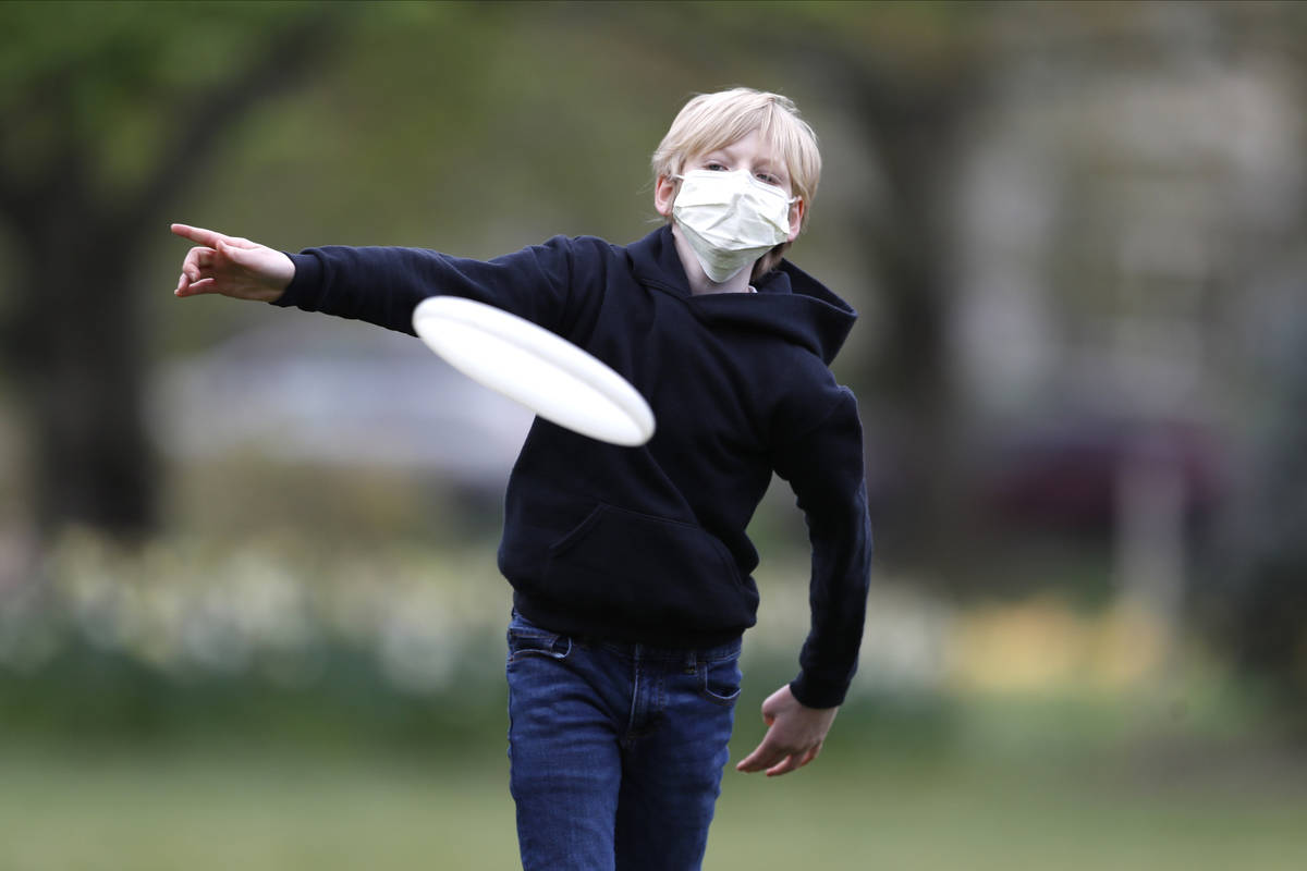 Shawn Cotter, 11, wears a face mask as he throws a Frisbee while playing catch with his father ...