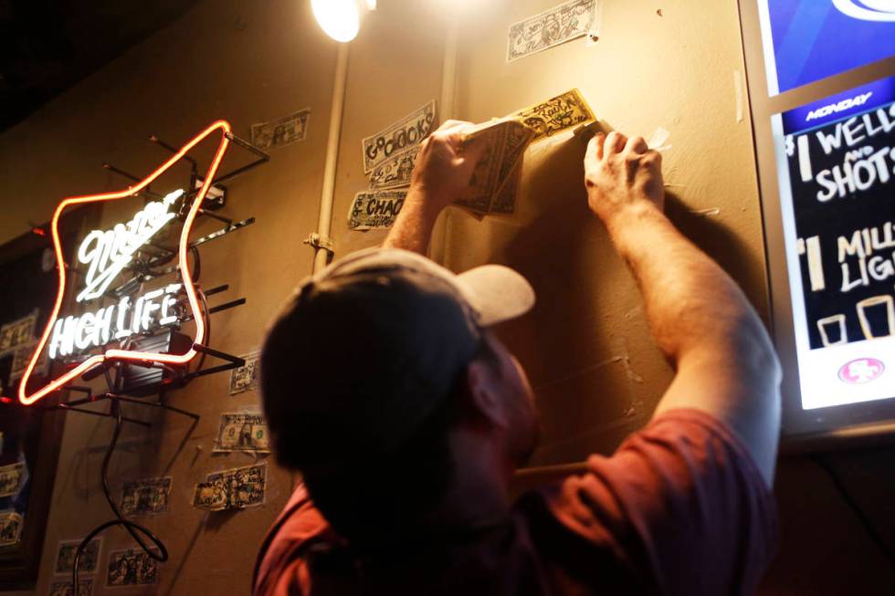 General manager David Hartley removes one dollar bills from the wall at the Boar's Head Lounge ...