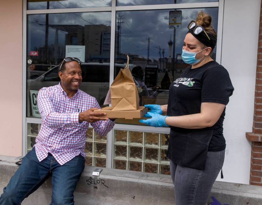 Vegenation customer Jamie Reid, left, receives his order from Rebecca Lemperle as part of their ...