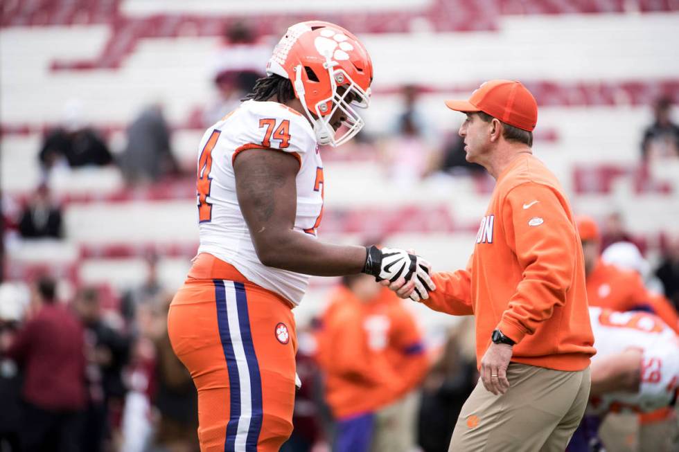 Clemson head coach Dabo Swinney shakes hands with offensive lineman John Simpson (74) before an ...