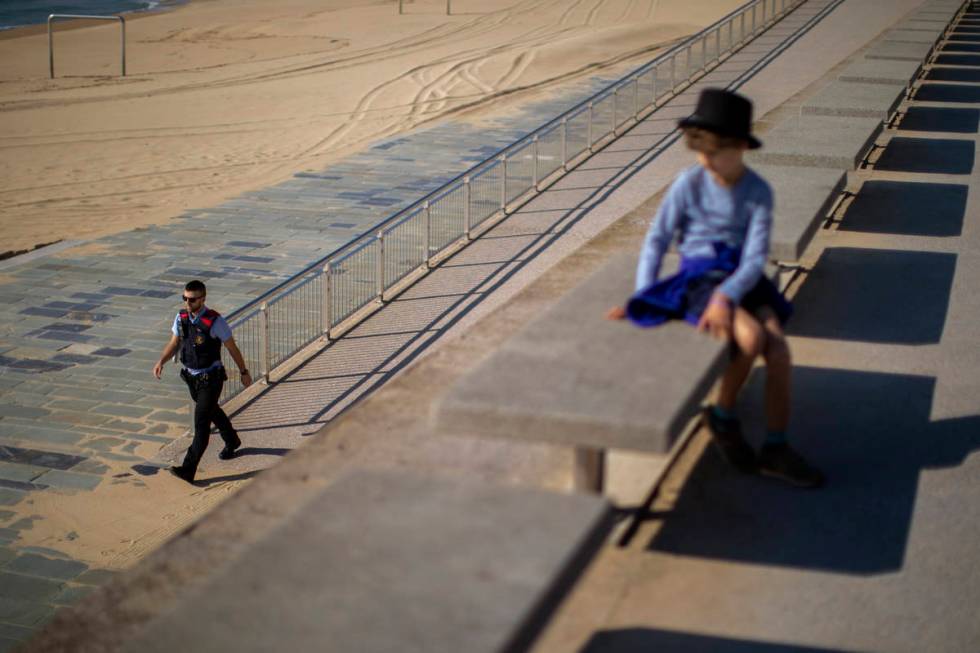 A child looks as a police officer patrols the promenade of the beach, where access is prohibite ...