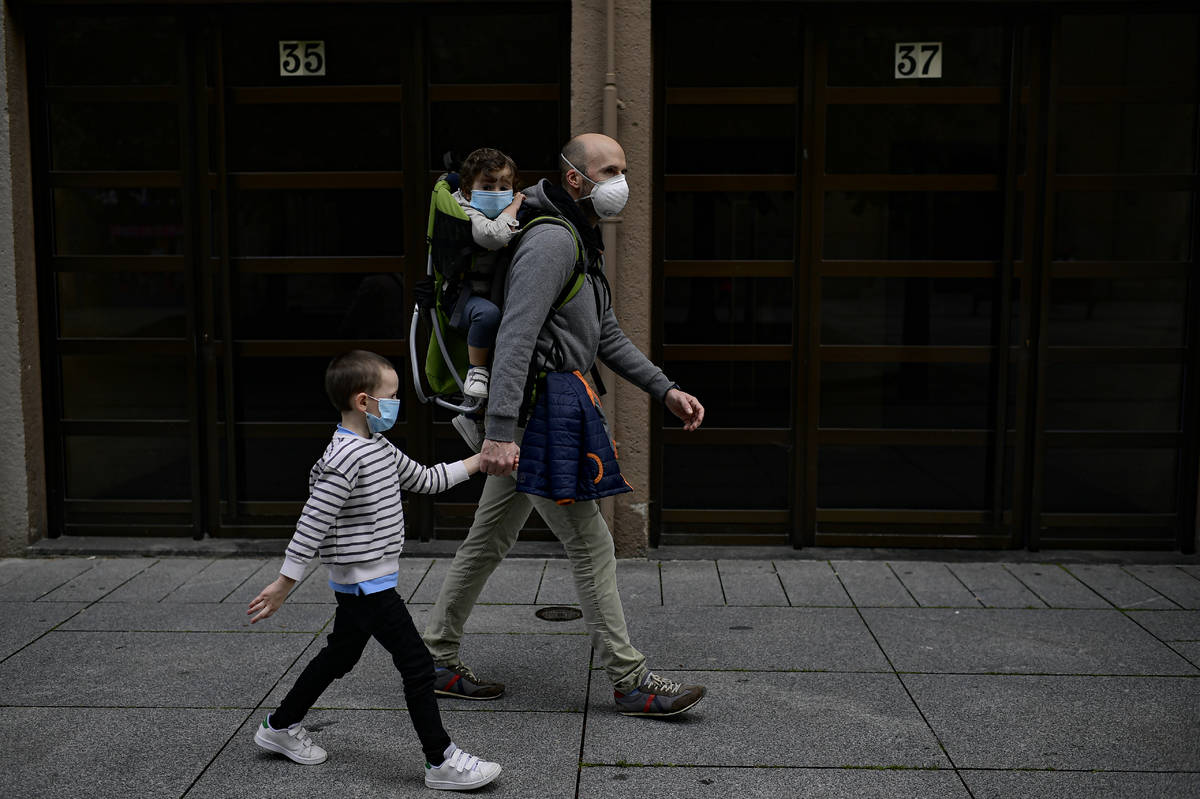 A father with his children wearing face mask to prevent the coronavirus go for a walk at Carlos ...