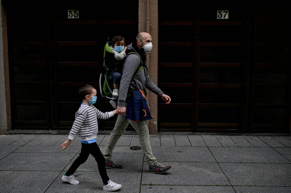 A father with his children wearing face mask to prevent the coronavirus go for a walk at Carlos ...