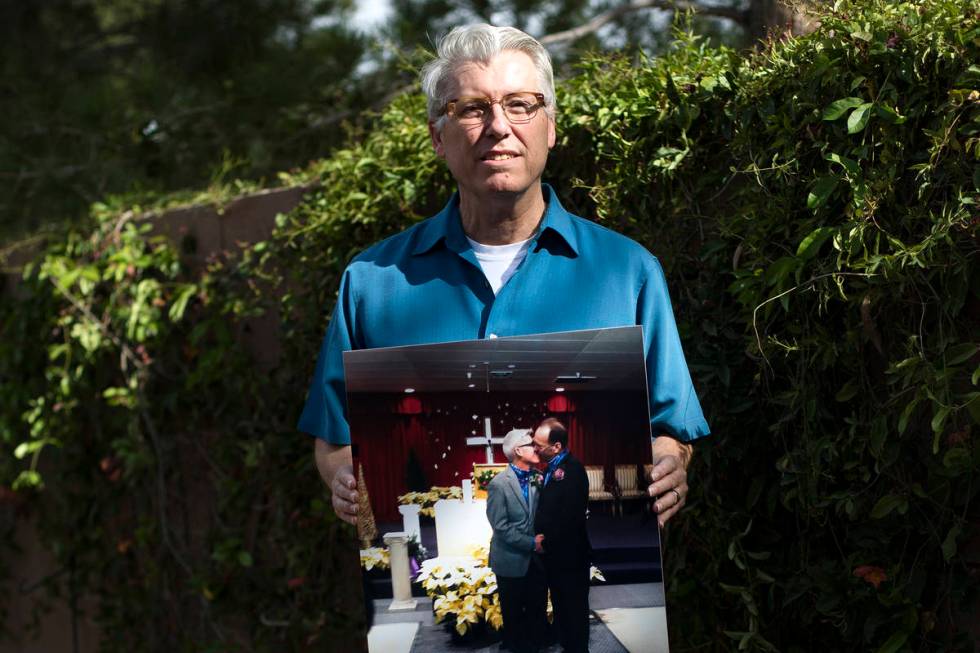 Richard Davis holds a photo of him and his husband Jeff Moore on their wedding day at his home ...