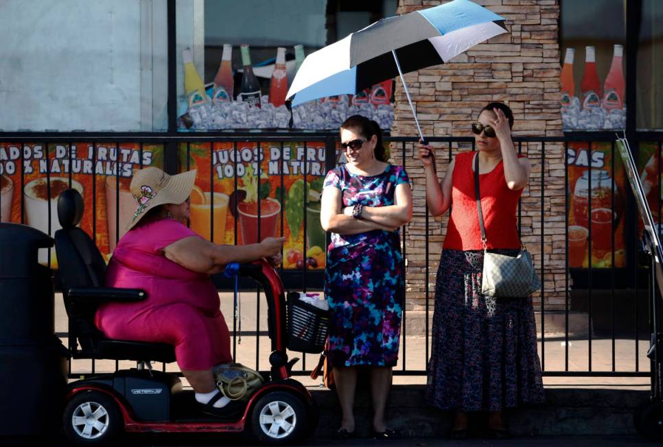 Commuters, who declined to give their names, wearing large hat and holding un umbrella to prote ...