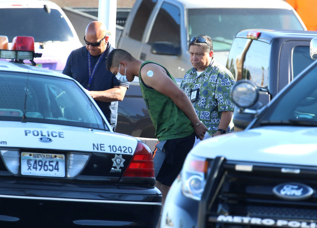 Las Vegas police officers lead a handcuffed man to an awaiting police vehicle near an apartment ...