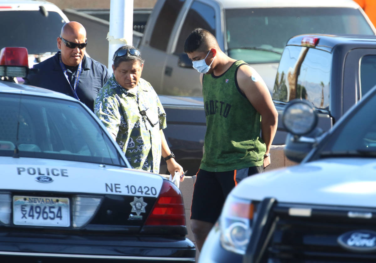 Las Vegas police officers lead a handcuffed man to an awaiting police vehicle near an apartment ...