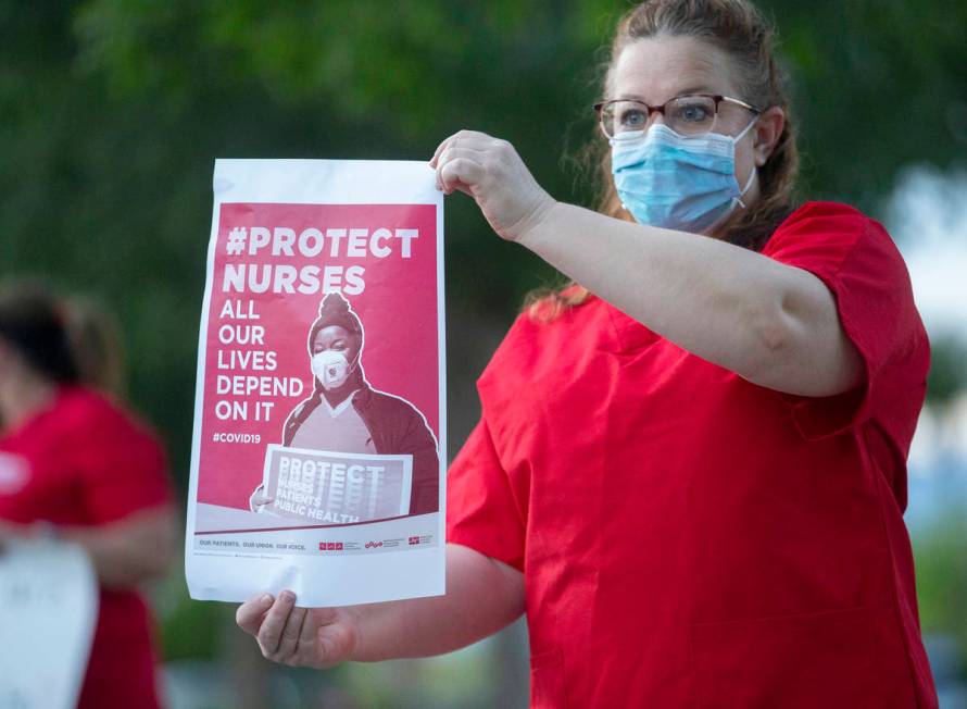 Labor and delivery nurse Jill Cassell holds a sign advocating for better protection, testing an ...