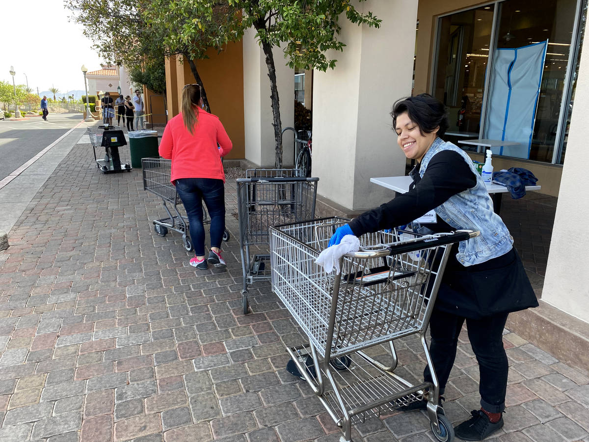 A worker sanitizes carts at Whole Foods at 8855 W. Charleston Blvd. in Las Vegas Tuesday, March ...