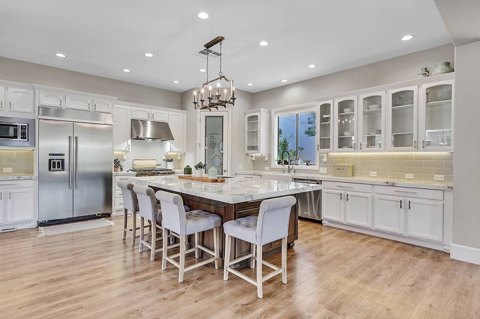 Huntington & Ellis The kitchen features KitchenAid appliances, a large center island and porcel ...