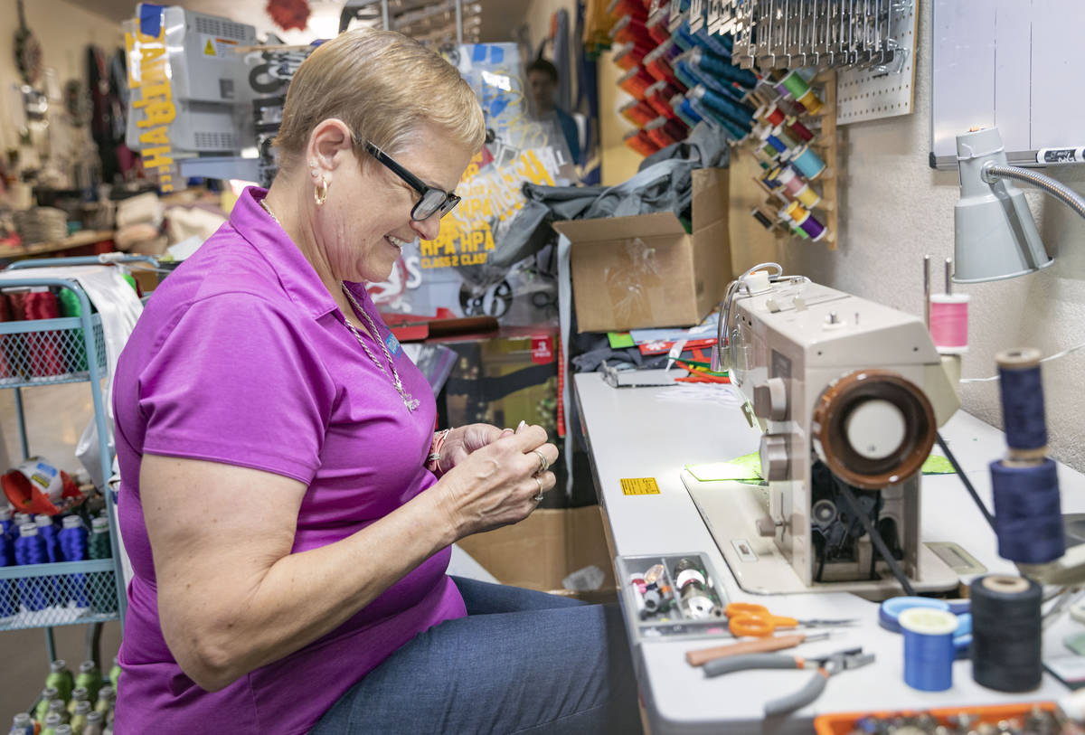 Michele Walker, owner of Imaginations Unlimited, sews a cloth face covering, in her embroidery ...