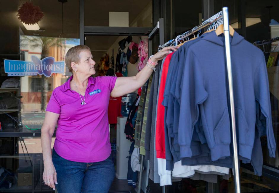 Michele Walker, owner of Imaginations Unlimited, organizes clothes out on the sidewalk to visua ...