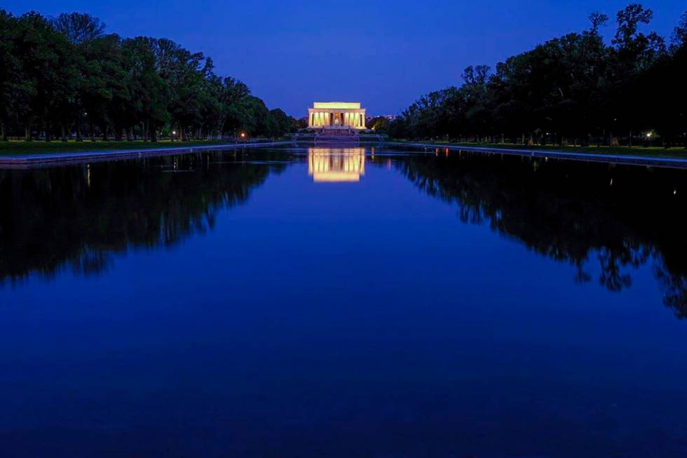 The Lincoln Memorial is reflected in the still waters of the reflecting pool on the National Ma ...