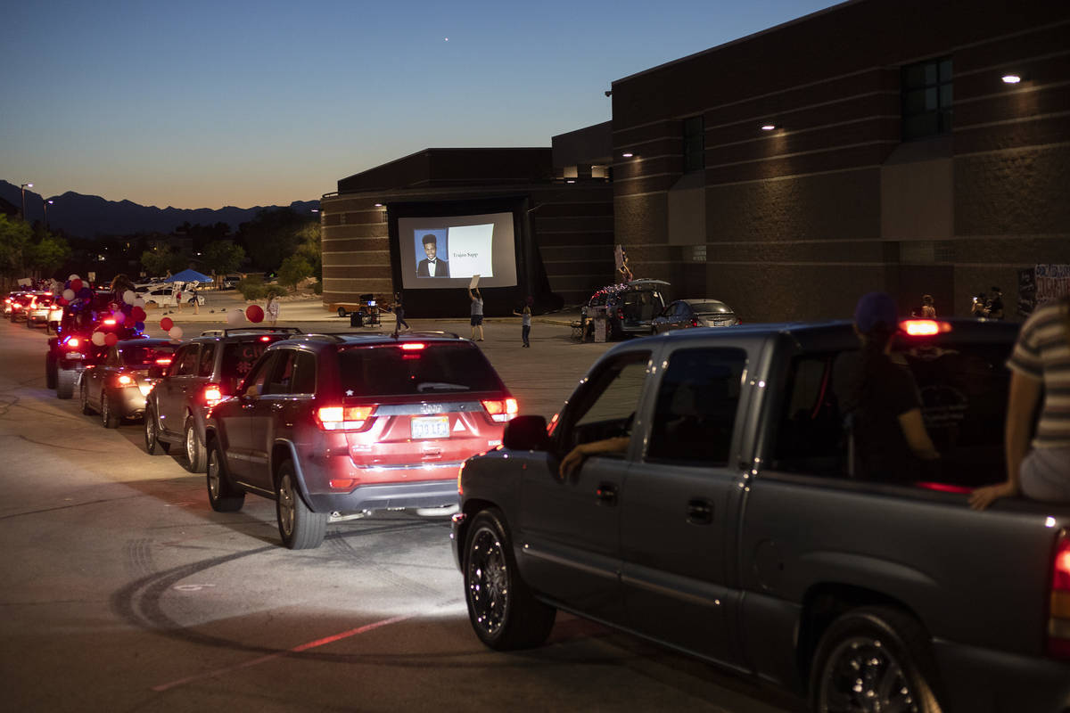 A screen flashes through a slideshow of graduating seniors' photos during a drive-through parad ...