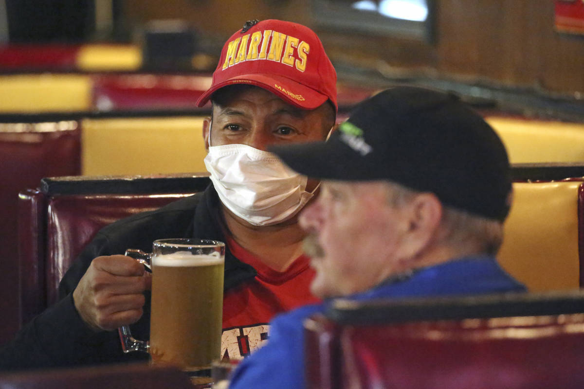 Cheers to You patron Clifford Pesheep, left, wears a mask before drinking his beer at the bar F ...