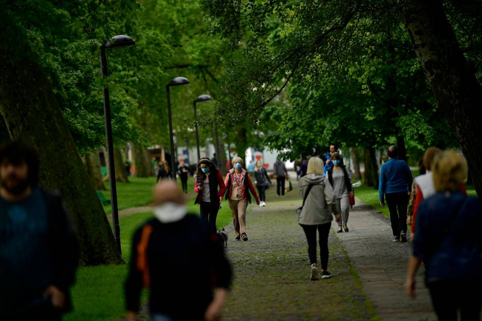 People wearing face masks to prevent the spread of coronavirus walk along Vuelta del Castillo p ...