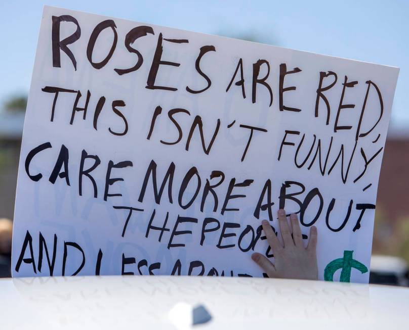 A sign protesting the possible new hockey arena in Henderson is held out of a car sunroof durin ...