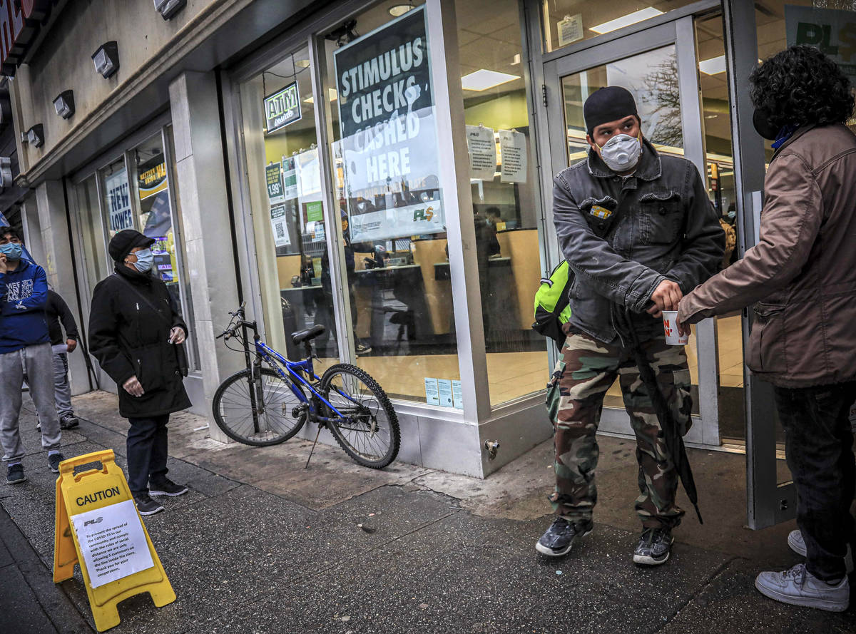 In this April 24, 2020, photo, a man holds out a cup for money donations, left, as customers we ...