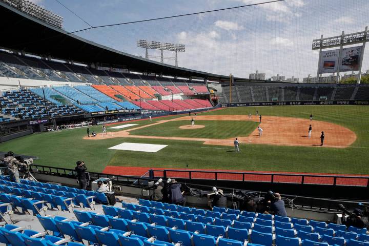 Photographers and TV camera work near empty seats during the pre-season baseball game between D ...