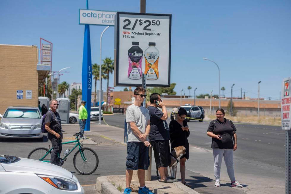 Individuals watch as the Las Vegas police investigate a downtown shooting in the 1900 block of ...