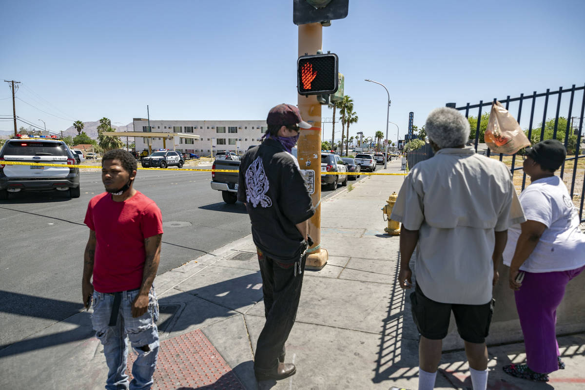 Individuals watch as the Las Vegas police investigate a downtown shooting in the 1900 block of ...