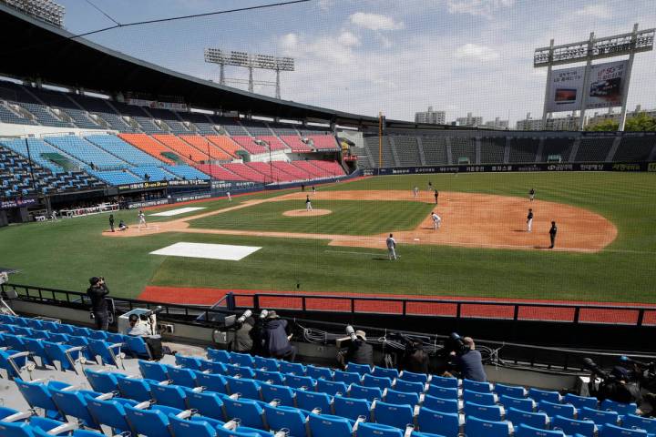 Photographers and TV camera work near empty seats during the pre-season baseball game between D ...