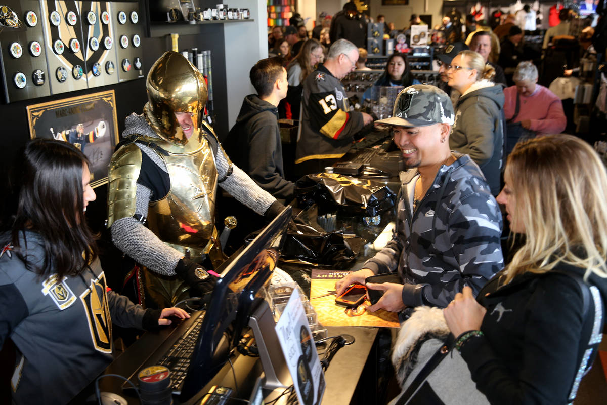 The Golden Knight steps in to help Vivika Kim, left, ring up Mike and Stephanie Ibasco of Mount ...