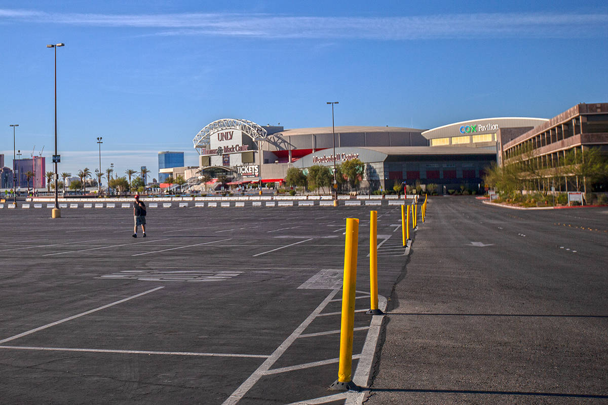 A single pedestrian walks through the empty parking lot of the Thomas & Mack Center on Satu ...