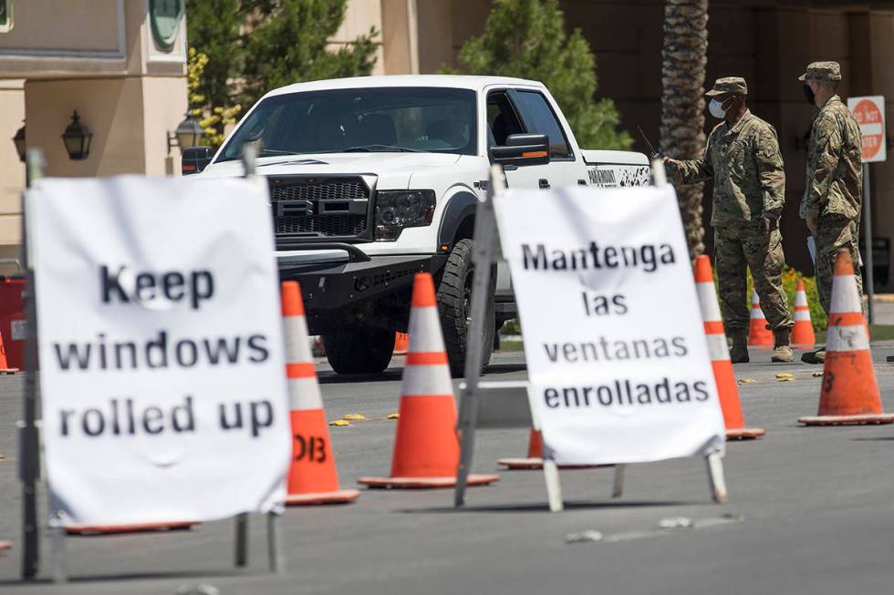 Members of the Nevada National Guard direct a person at the COVID-19 drive-through testing at ...