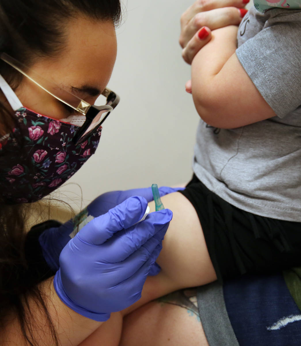 Olivia Hippert, 2, and her mother Amanda watch as Samantha Vizcaino, a medical assistant, vacci ...