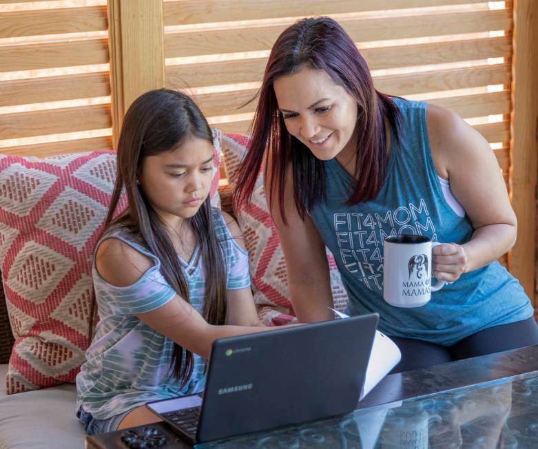 Owner of FIT4MOM Las Vegas Jessica Peralta helps her daughter Grace, 9, with her online schooli ...