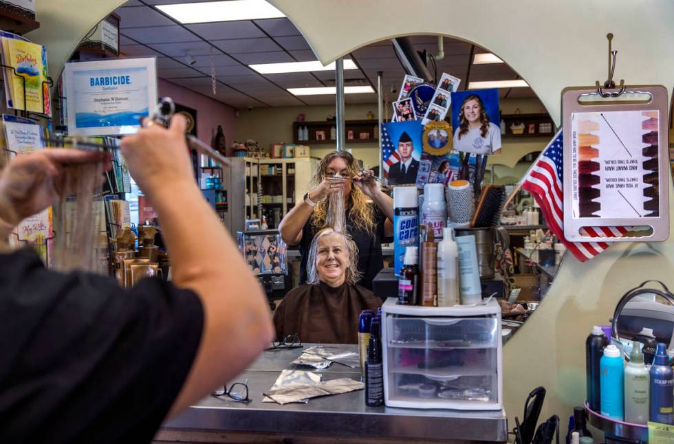 Owner Stephanie Wilkerson, top, cuts the hair of customer Louise Bustillos as business resumes ...