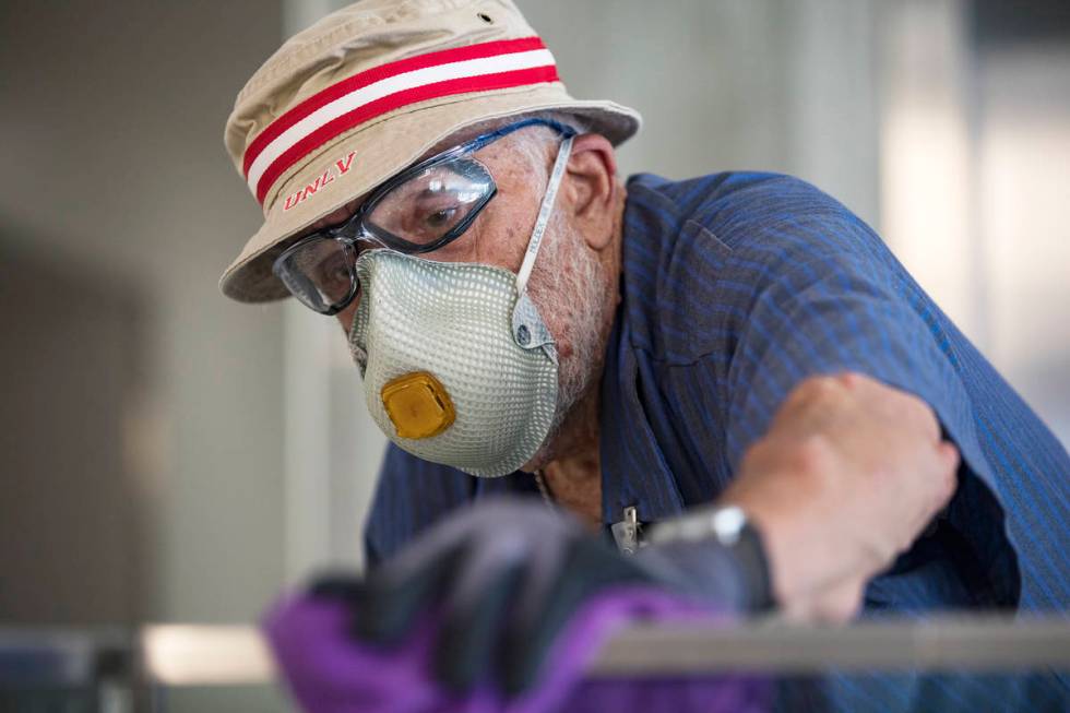 Custodian Jarrell Siler sanitizes handrails in the Hospitality Hall at UNLV in Las Vegas, Thurs ...